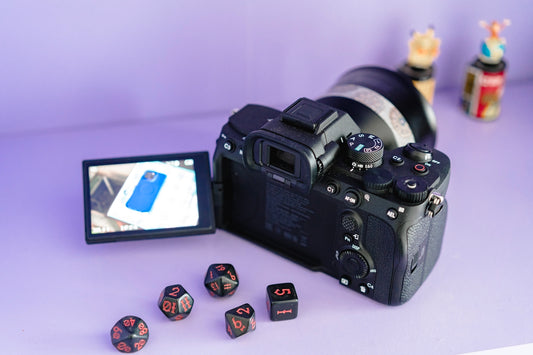 Camera with dice and phone screen on purple background.